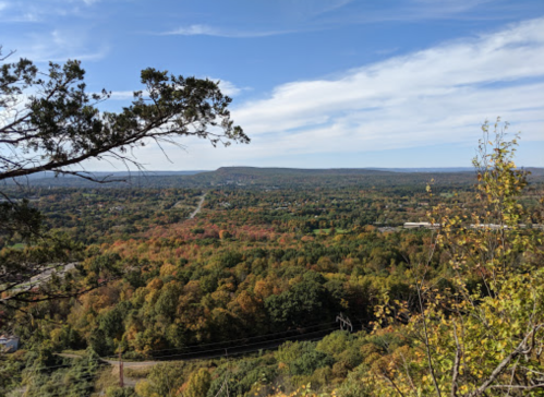 A panoramic view of a colorful autumn landscape with rolling hills and a clear blue sky.
