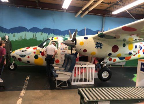 A colorful, polka-dotted airplane inside a museum, with visitors exploring its interior and nearby displays.