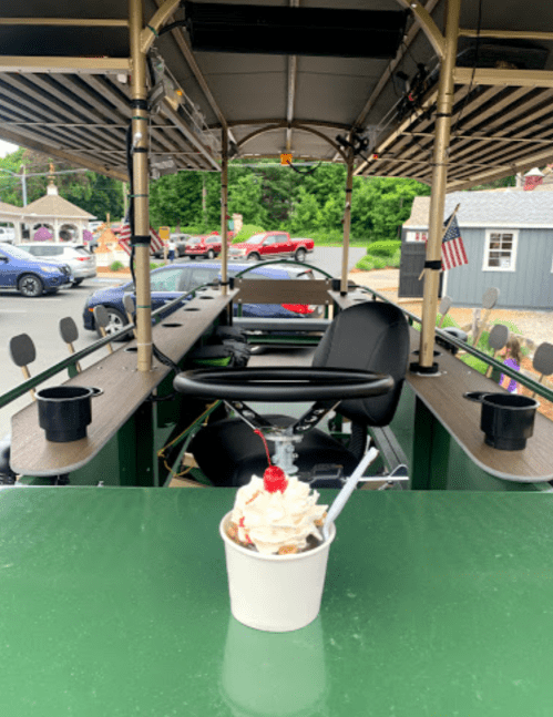 A view from inside a pedal-powered vehicle, with a dessert in the foreground and a scenic outdoor setting behind.