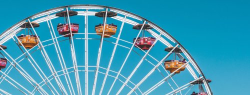 A colorful Ferris wheel against a clear blue sky, featuring yellow and red gondolas.