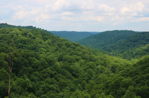Lush green hills stretch across the landscape under a partly cloudy sky.