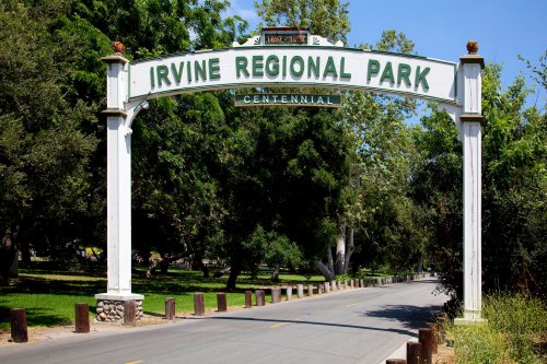 Sign at the entrance of Irvine Regional Park, framed by trees and a clear blue sky.