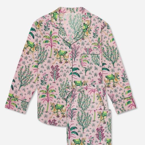 A pink pajama set featuring a vibrant botanical print with trees and flowers in green and purple hues.