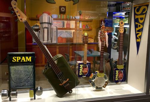 Display of unique musical instruments made from Spam cans and other materials, set in a colorful diner backdrop.