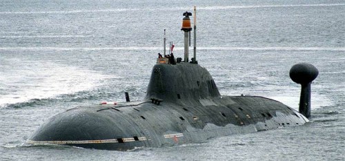 A submarine surfaces in calm waters, showcasing its sleek, dark hull and distinctive conning tower.