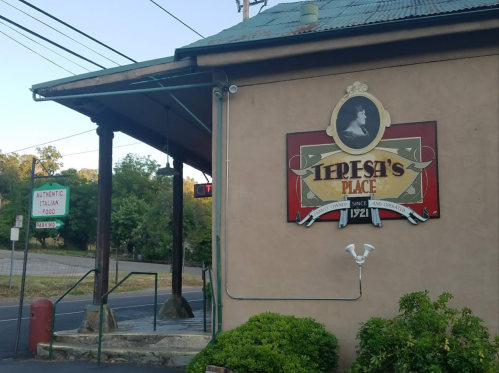 Sign for "Iepesi's Place," an Italian restaurant, with a vintage design and outdoor seating area.