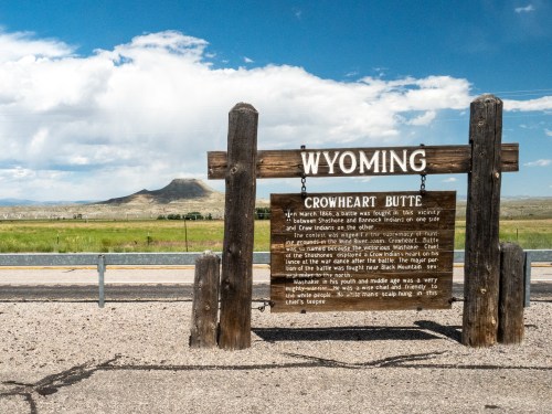 Sign for Crowheart Butte in Wyoming, with a scenic view of the butte and surrounding landscape in the background.