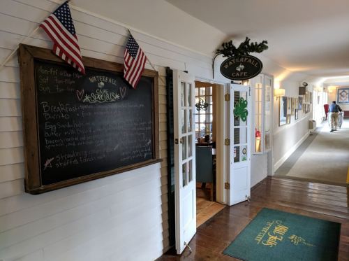Entrance to Waterfall Café with a chalkboard menu, flags, and a welcoming hallway.