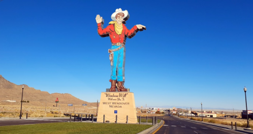 A large cowboy statue stands at the entrance of West Wendover, Nevada, against a clear blue sky.