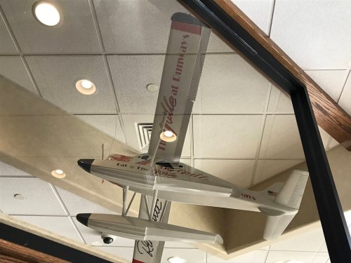 A model airplane displayed on a ceiling, reflecting light in a restaurant setting.