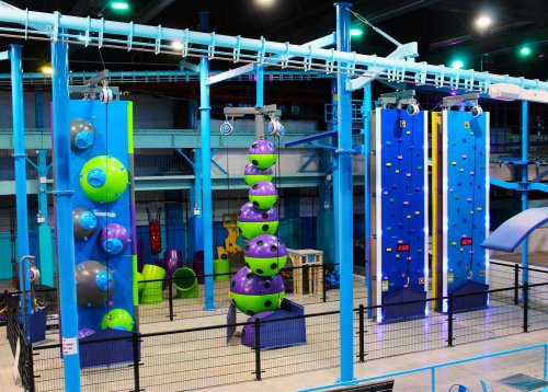 Indoor climbing facility featuring colorful climbing walls and structures, with various climbing challenges and equipment.
