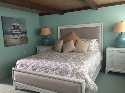 A cozy bedroom featuring a large bed with decorative pillows, two bedside tables, and light blue walls.