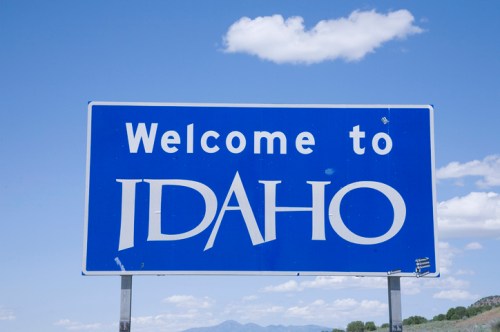 A blue welcome sign for Idaho against a clear sky with clouds.