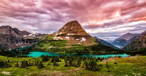 A stunning mountain landscape with a vibrant lake, surrounded by lush greenery and dramatic clouds at sunset.