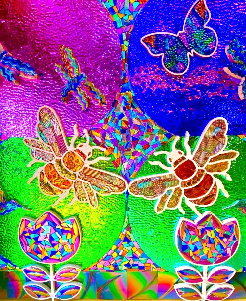 Colorful stained glass featuring butterflies, bees, and flowers in vibrant hues of purple, blue, green, and pink.
