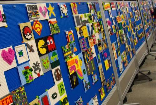 A colorful display of pixel art made from LEGO bricks on blue boards, featuring various characters and designs.