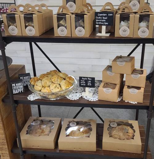 A display shelf with assorted baked goods, including pies and pastries, neatly packaged and labeled.