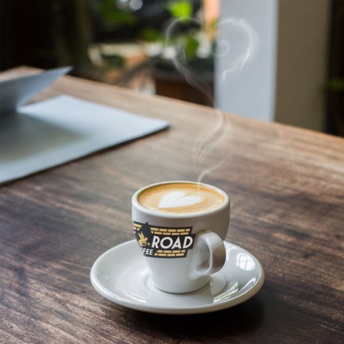 A steaming cup of coffee with a heart-shaped foam design on a wooden table.