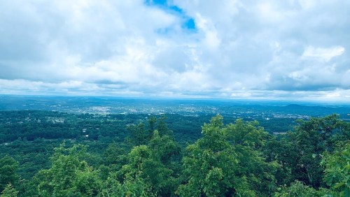 A panoramic view of lush green hills and valleys under a cloudy sky.