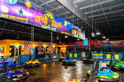 Colorful indoor bumper car arena with a vibrant banner and various bumper cars ready for action.