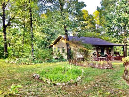 A cozy house surrounded by trees, with a garden and wooden fence in a serene, green setting.