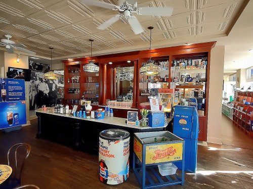 A vintage-style bar with a wooden counter, shelves of drinks, and retro decor in a bright, inviting space.