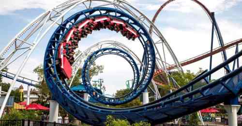 A roller coaster with a loop, featuring riders enjoying the thrill against a clear sky.