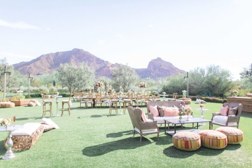 Elegant outdoor event setup with seating, tables, and mountain backdrop under a clear sky.