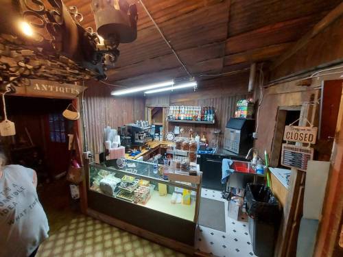 A cozy, rustic shop interior with a counter, shelves of products, and a closed sign hanging on the wall.