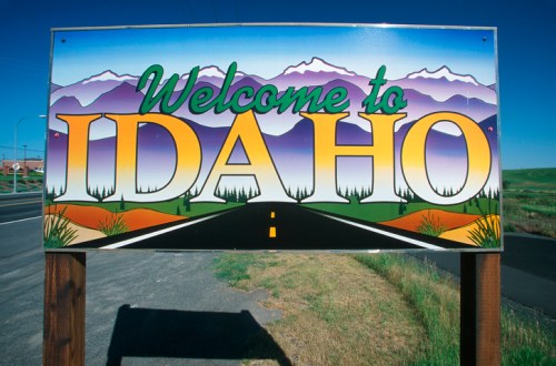 Colorful "Welcome to Idaho" sign featuring mountains and a road, set against a clear blue sky.