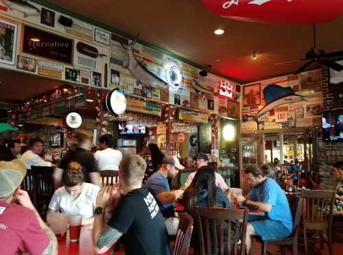 A lively restaurant interior with colorful decor, patrons at tables, and a bar area filled with memorabilia.