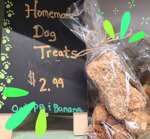 A sign for homemade dog treats priced at $2.99, with treats displayed in a clear bag.