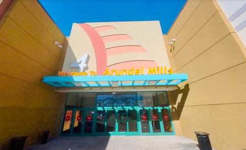 Entrance of Arundel Mills shopping mall with colorful signage and blue awning under a clear blue sky.