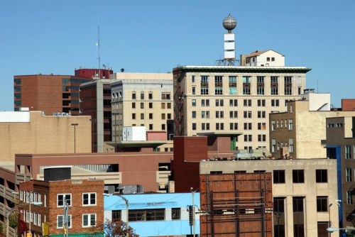 A city skyline featuring a mix of modern and historic buildings under a clear blue sky.