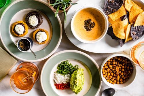 A colorful spread of various dishes, including soup, chips, and small desserts, arranged on a table.