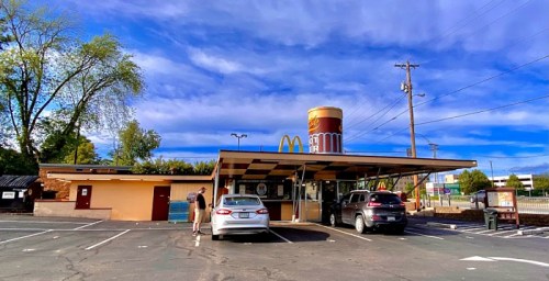 A McDonald's restaurant with a unique design, featuring a large cup on the roof and cars parked in front.