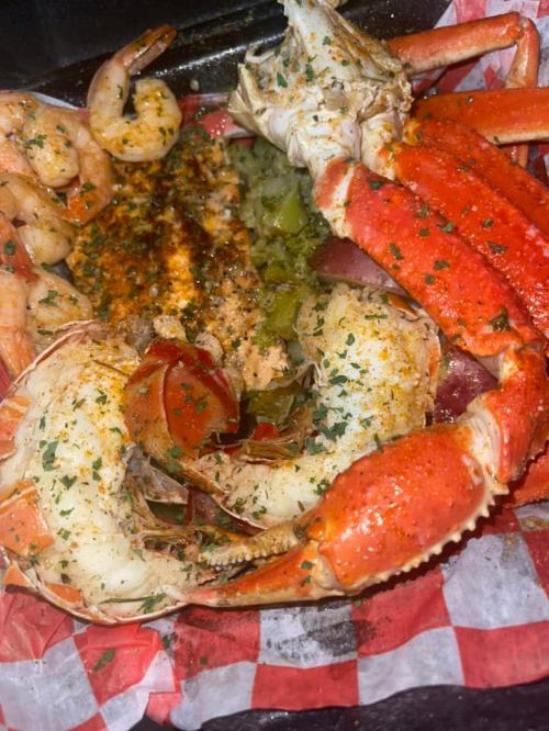 A close-up of a seafood platter featuring shrimp, crab legs, and seasoned lobster, garnished with herbs.