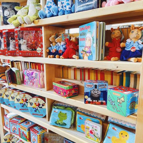 Colorful shelves filled with children's books, toys, and plush animals in a cozy store setting.