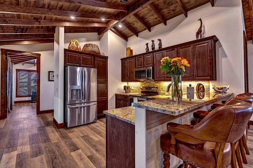 A modern kitchen with dark wood cabinets, stainless steel appliances, and a granite countertop, featuring decorative accents.