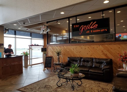 Interior of a restaurant called "The Grille at Runways," featuring a reception area and cozy seating.