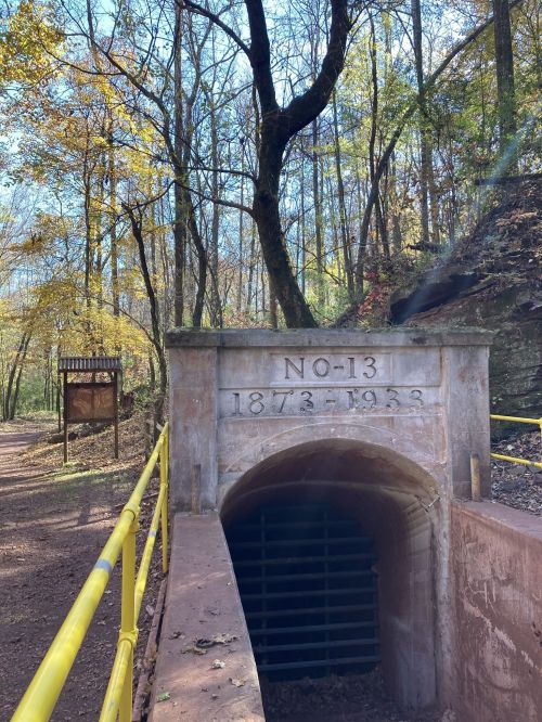 Historic stone tunnel entrance marked "NO-13 1873-1938," surrounded by trees and autumn foliage.