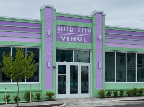 Exterior of Hub City Vinyl, a colorful building with purple and green stripes, featuring large windows and a welcoming entrance.