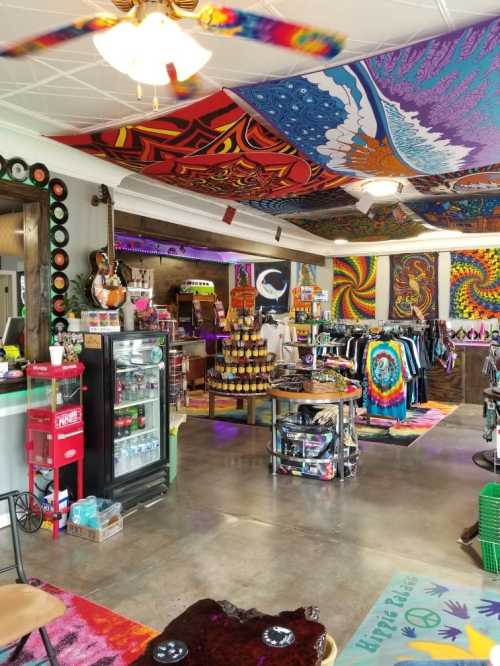 A vibrant shop interior with colorful psychedelic decor, clothing racks, and a display of snacks and drinks.