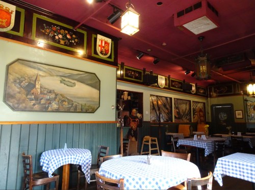Cozy restaurant interior with checkered tablecloths, wall art, and warm lighting.