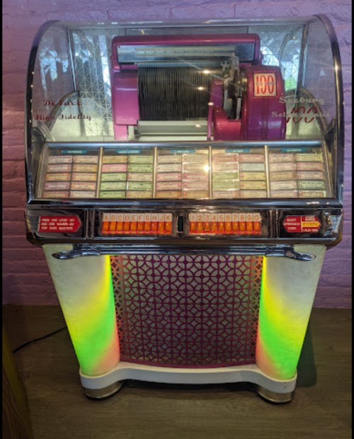 A vintage jukebox with colorful lights, featuring a selection of music buttons and a classic design.