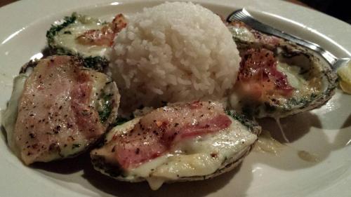 Baked oysters topped with cheese and bacon, served with a side of white rice.
