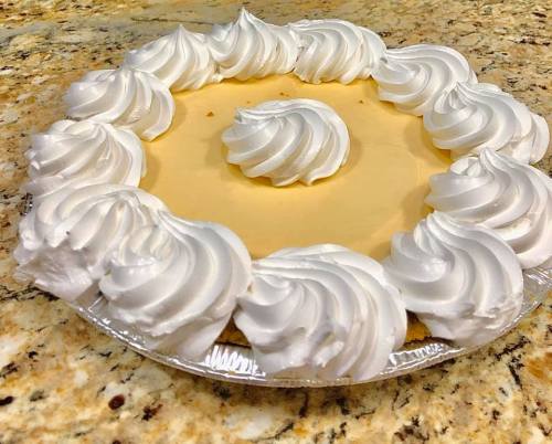 A creamy pie topped with swirls of whipped cream, set on a granite countertop.