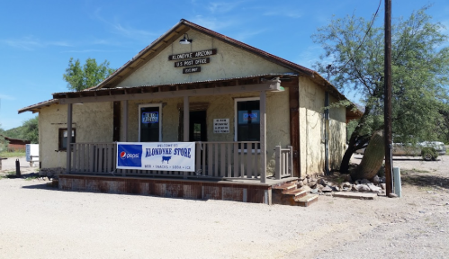 A rustic store in Klondyke, Arizona, with a porch and a Pepsi banner, surrounded by desert landscape.