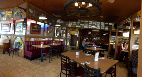 A cozy restaurant interior with wooden decor, booths, and walls adorned with vintage license plates and artwork.