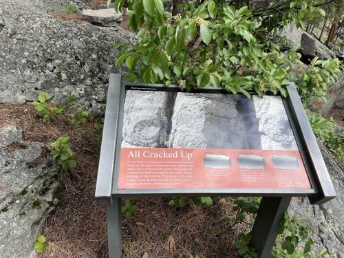 A sign titled "All Cracked Up" near rocky terrain, explaining geological features and cracks in the rocks.